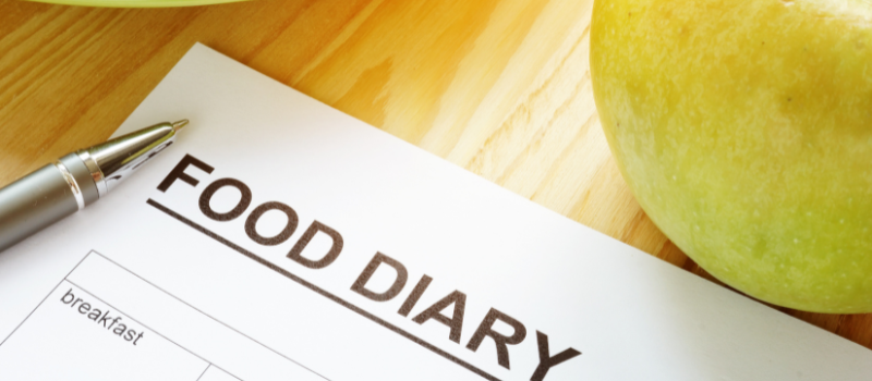 Notitieboek met 'Food Diary' en een appel voor dieetregistratie.