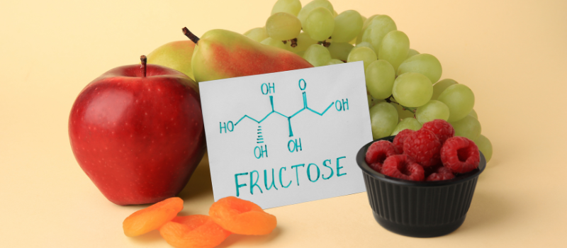 Fruitsamenstelling met appel, druiven, frambozen en een schema van fructose.