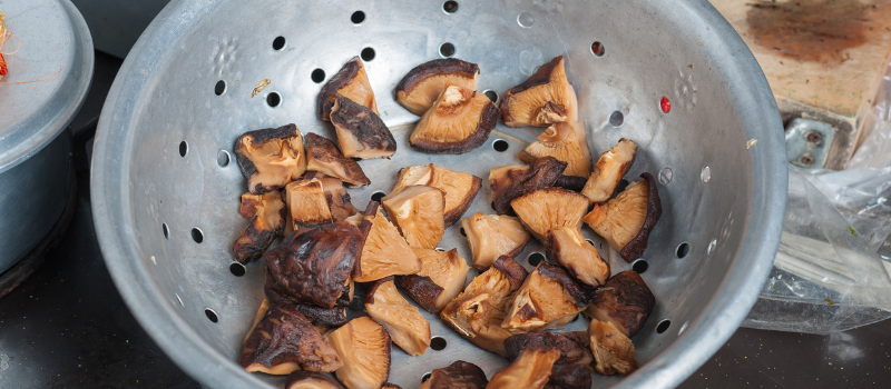 Gekookte shiitake paddenstoelen in een metalen vergiet.