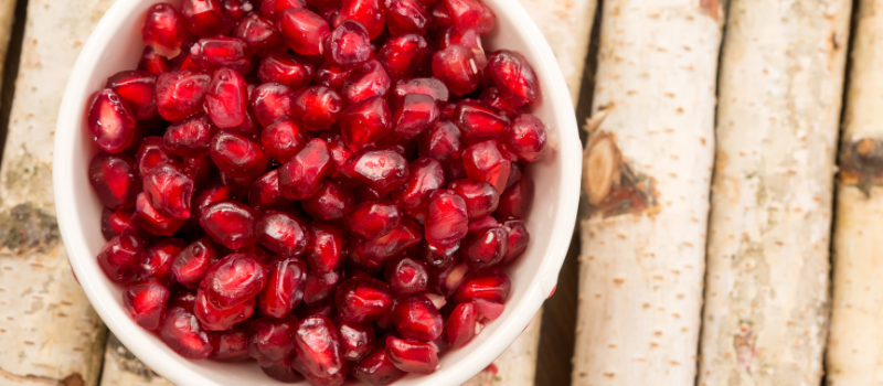 Kom met glanzende granaatappelpitten op houten ondergrond, gezond snackfruit