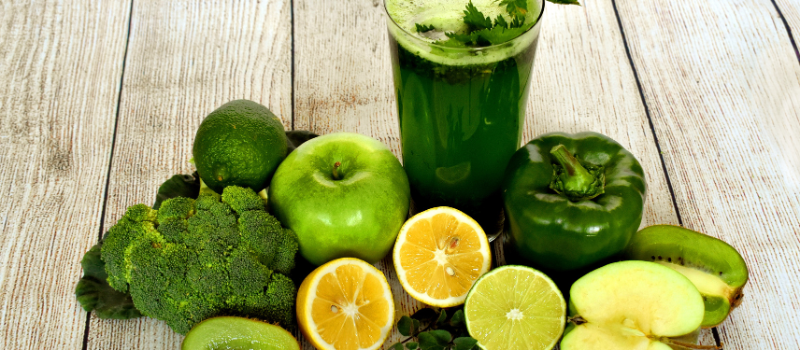 Glas groene smoothie met citrusfruit, broccoli en appels op houten tafel