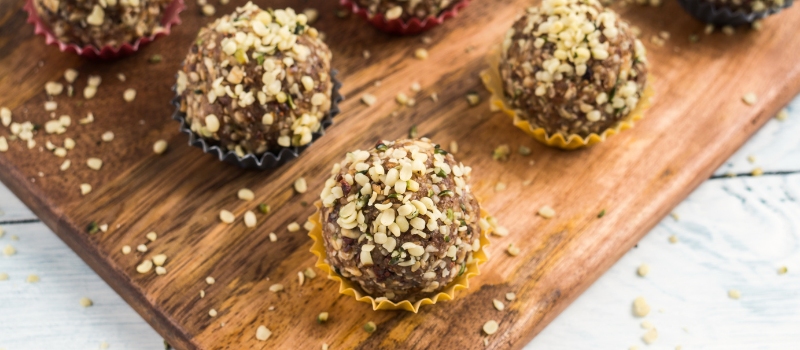 Gezonde energieballen met hennepzaad topping, geserveerd op een houten plank.