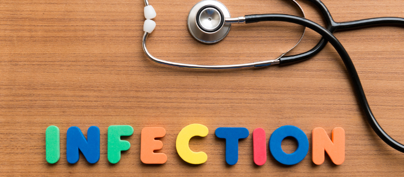 Het woord ‘infection’ met stethoscoop op houten ondergrond