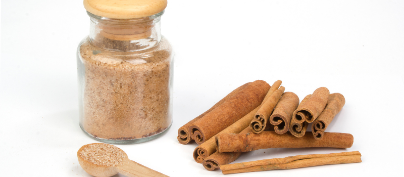 Pot met bruine kaneelsuiker en groep kaneelstokjes, specerij en baking ingredient