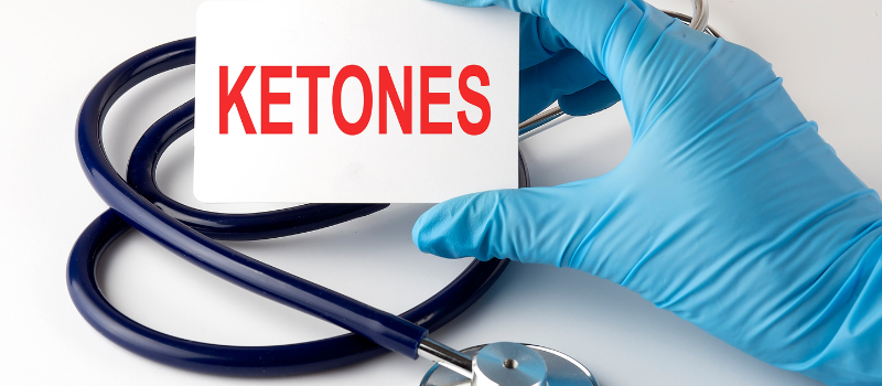 Hand met handschoen houdt kaart met ‘ketones’, medische context vetverbranding