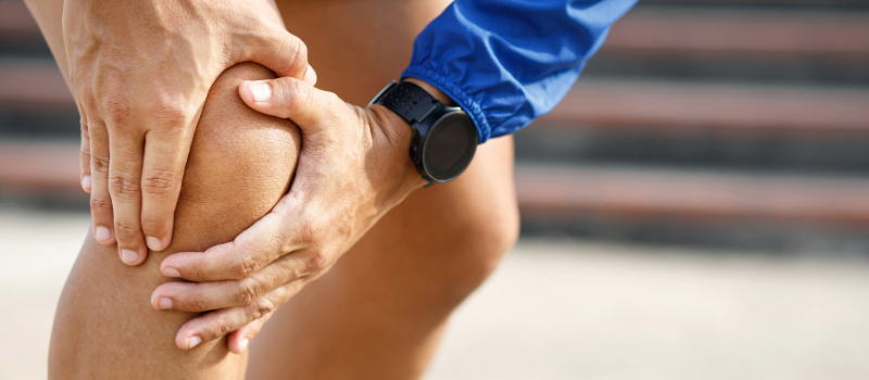 Persoon grijpt naar knie vanwege pijn, mogelijke ontsteking