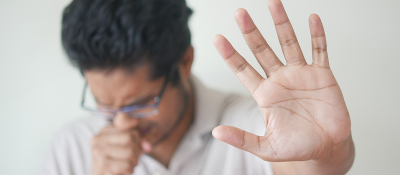 Man hoest met hand omhoog als teken van besmetting, kinkhoest