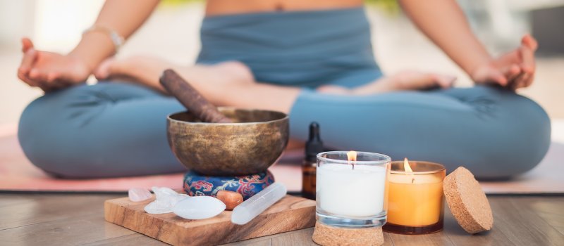 Mediterende vrouw met kaarsen en edelstenen op yogamat