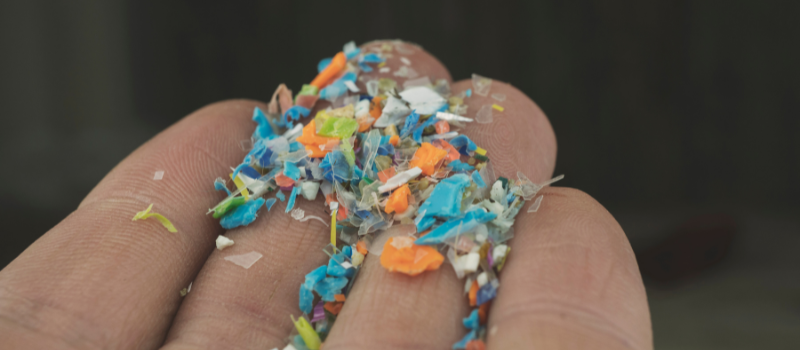 Hand met kleurrijke microplasticdeeltjes als vervuilingsprobleem