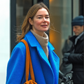 Vrouw in blauwe jas loopt ontspannen door de stad als illustratie bij de cursus Mindful Energy: Innerlijke Rust.