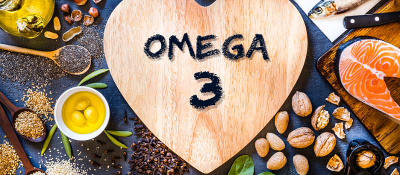 Omega 3 geschreven op hartvormig bord omringd door vis en noten