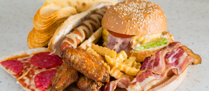 Bord met fastfood zoals burger, pizza, friet en bacon