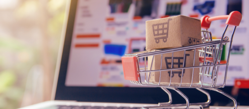 Mini winkelwagentje met dozen op laptop bij online shoppen