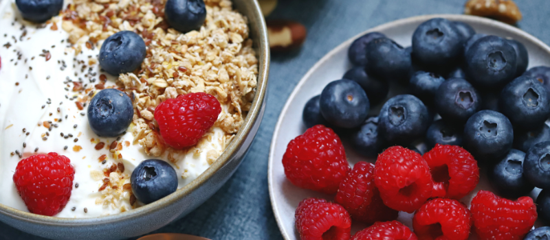Kom met yoghurt, granola, blauwe bessen en frambozen