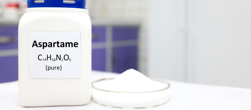 Witte pot met label 'Aspartame' en poeder in laboratoriumomgeving