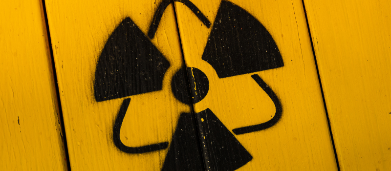 Zwart radioactief symbool op gele houten achtergrond, gevaarlijke stoffen