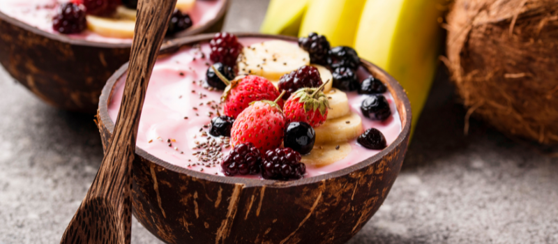 Smoothiebowl geserveerd in een halve kokosnoot met bessen, banaan en chiazaad.