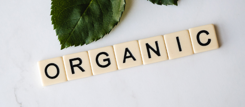 Tegels met tekst organic en groene bladeren op witte achtergrond