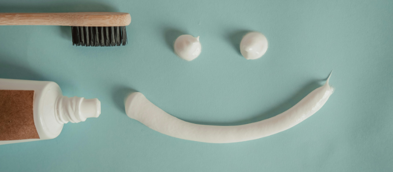 Smiley van tandpasta en houten borstel op blauwe achtergrond