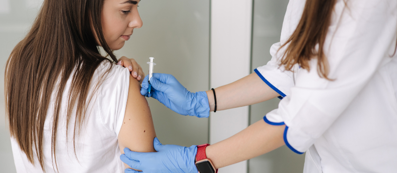 Meisje krijgt injectie in bovenarm, vaccin tegen kinkhoest