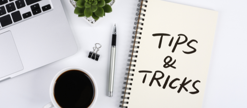 Notitieboek met tekst tips & tricks naast laptop en koffie, blauw licht tips