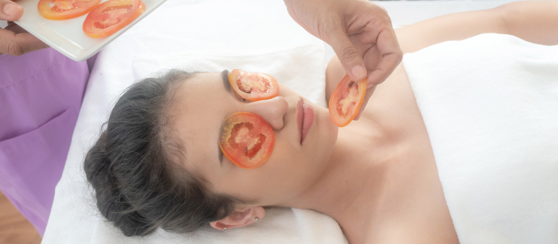 Vrouw krijgt tomatenmaskerbehandeling voor een gezonde huid.