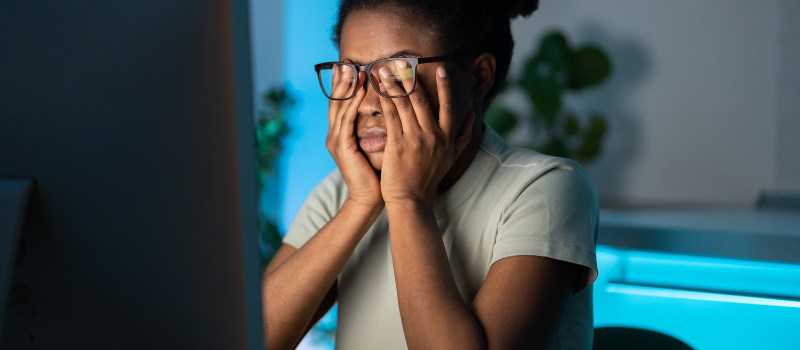 Vrouw met bril wrijft in vermoeide ogen door blauw licht