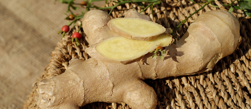 Verse gemberwortel met plakjes op een mand, natuurlijke achtergrond.