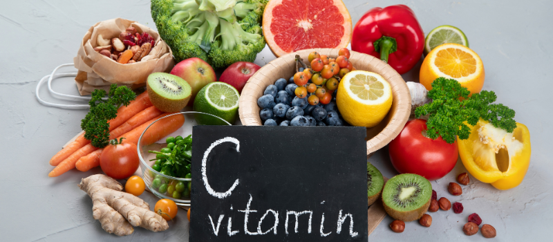 Assortiment citrusvruchten en groenten met bordje “Vitamin C”, gezond eten