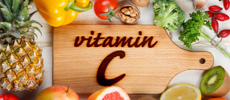Houten plank met tekst vitamine C en diverse groenten en fruit eromheen