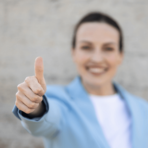 Vrouw in blauw colbert geeft duim omhoog met lach, symbool voor positieve verandering