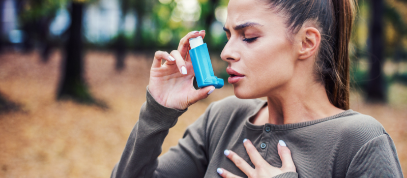Vrouw gebruikt blauwe inhalator tijdens benauwdheid in park