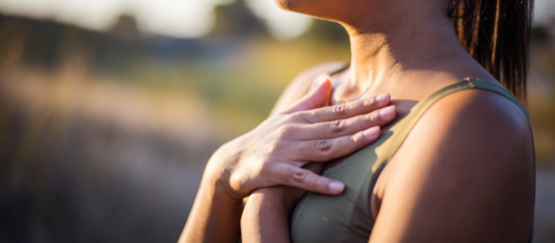 Vrouw met handen op borst in zonlicht, focus op zelfbewustzijn en gezondheid