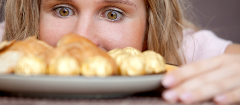 Vrouw kijkt naar een bord met croissants en gouden chocolade, nieuwsgierig.