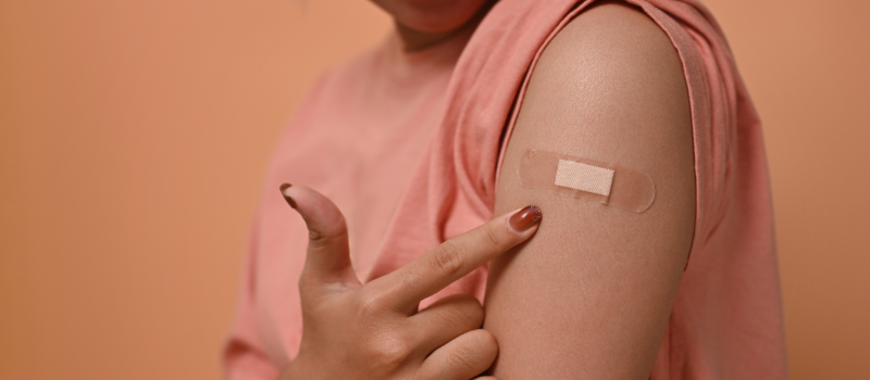 Vrouw wijst op pleister na vaccinatie tegen kinkhoest