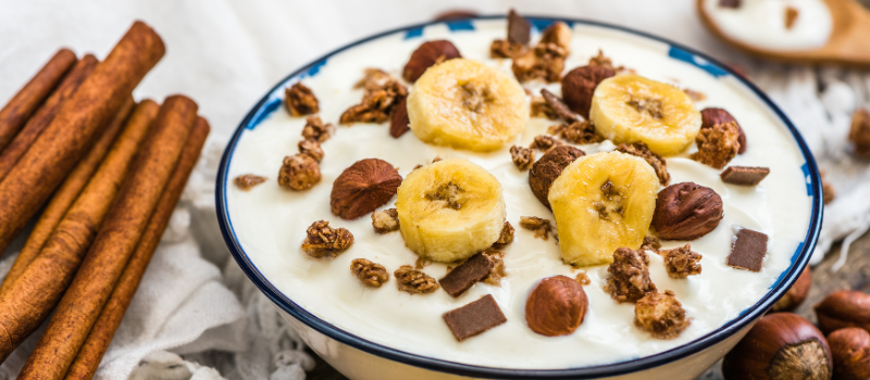 Yoghurt met plakjes banaan, granola, noten en chocoladestukjes.