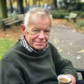 Portretfoto van Albert Konings buiten in een parkachtige omgeving met herfstbladeren.
