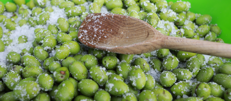 Gezouten groene olijven met houten lepel