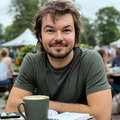 Portretfoto van Jesse Vreeken met een glimlach, zittend aan een tafel met een kopje koffie.