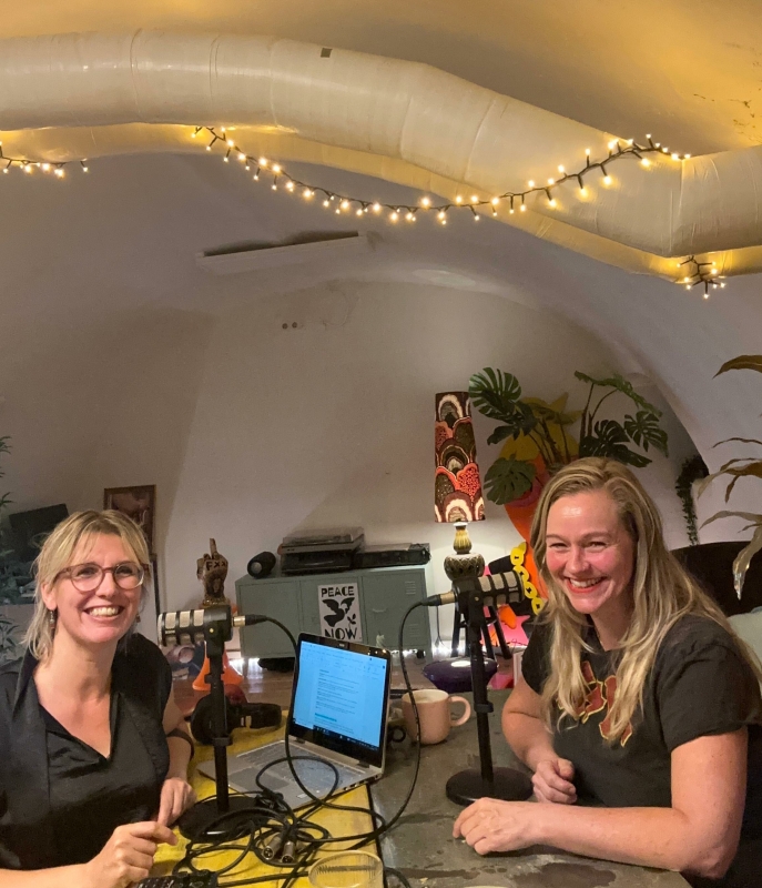 Twee vrouwen achter microfoons nemen een podcast op
