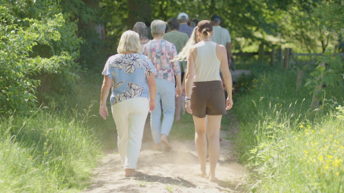 Deelnemers van VolZicht lopen samen een pad in de natuur tijdens de live dag, op weg naar natuurlijk beter zien