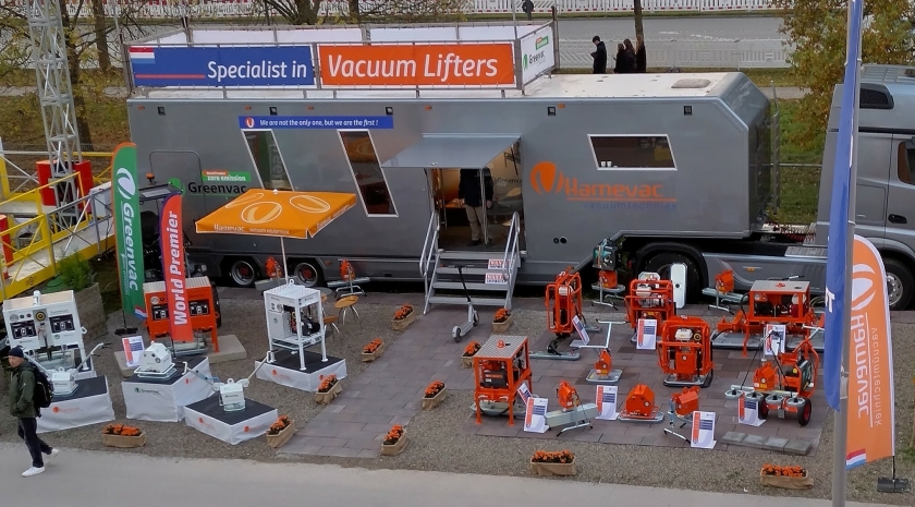 Stand van Hamevac op de BAUMA in München met een breed assortiment vacuümheffers, demonstratie-units en opvallende mobiele showroom, als toonbeeld van succesvolle productbemiddeling via van Oirschot.