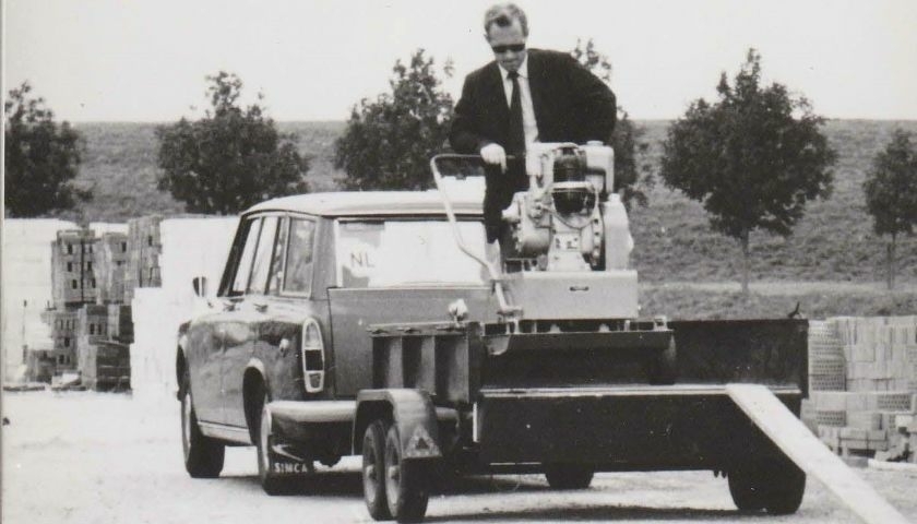 “Historic photo of Leo van Oirschot unloading self-developed VANO compactor and trailer at a construction site — early example of outsourced metal production”