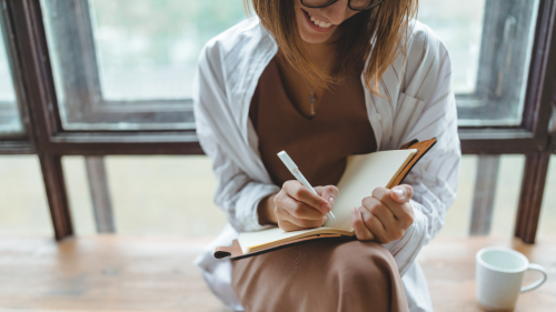 Vrouw lacht en schrijft in een schrift