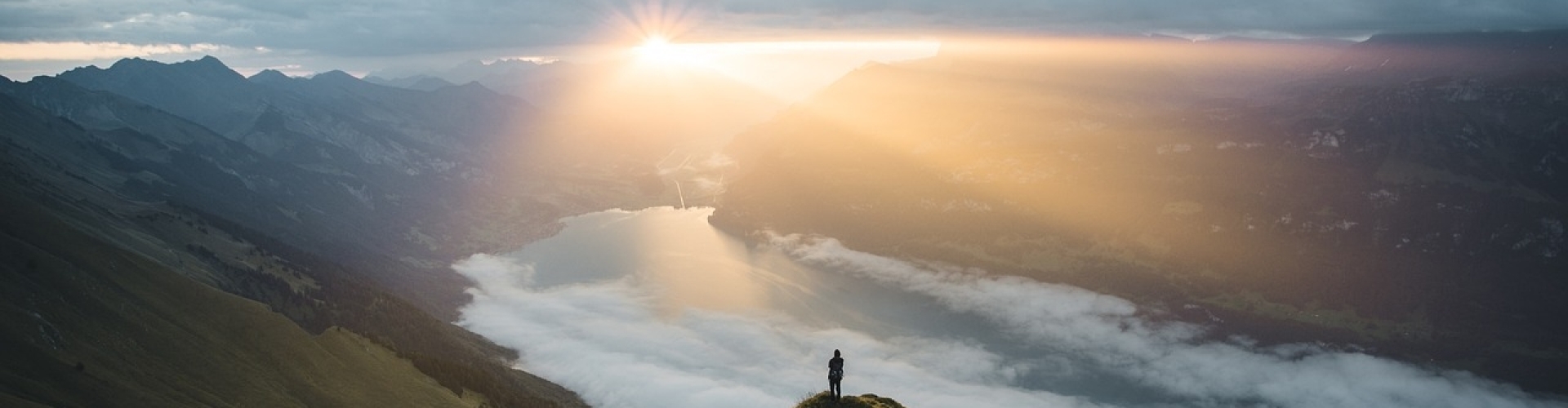 persoon op een heuveltop met zonsopkomst in de verte