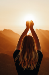 Vrouw lijkt de opkomende zon tussen haar handen te houden. Een spiritueel beeld.