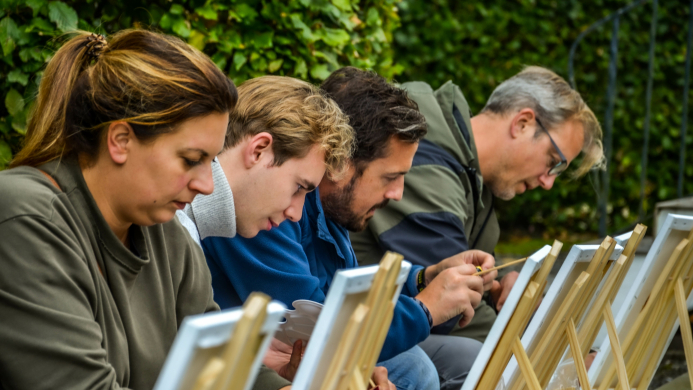 Teamleden van Oreon Properties werken aan een creatieve schilderopdracht tijdens een reflectieve teambuilding van YALPAK.