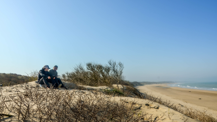 Team in gesprek in de duinen met uitzicht op het strand tijdens een tweedaagse YALPAK team experience aan de Côte d’Opale