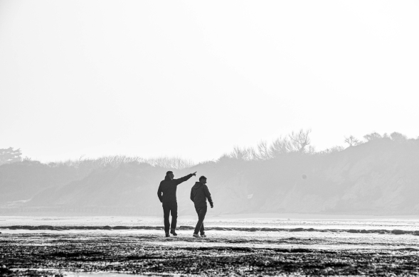 Twee teamleden in gesprek tijdens een strandwandeling aan de Côte d’Opale tijdens een YALPAK teamervaring