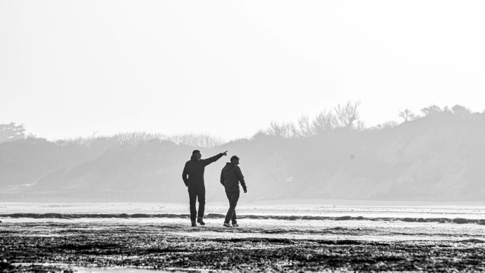 Twee teamleden in gesprek tijdens een strandwandeling aan de Côte d’Opale tijdens een YALPAK teamervaring